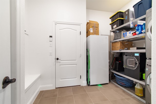 laundry area with tile patterned flooring and stacked washer and clothes dryer