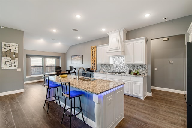 kitchen featuring an island with sink, white cabinets, sink, dark hardwood / wood-style flooring, and vaulted ceiling