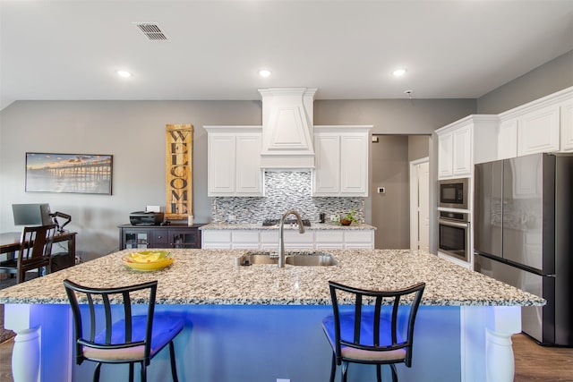 kitchen with appliances with stainless steel finishes, hardwood / wood-style flooring, white cabinetry, and a center island with sink