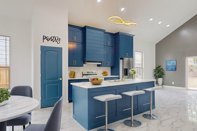 kitchen with appliances with stainless steel finishes, plenty of natural light, a center island with sink, and a breakfast bar