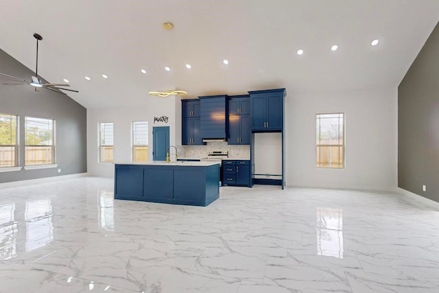 kitchen with tasteful backsplash, a center island with sink, blue cabinetry, vaulted ceiling, and ceiling fan