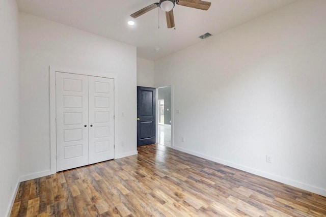 unfurnished bedroom featuring light hardwood / wood-style floors, ceiling fan, a high ceiling, and a closet