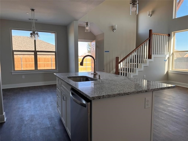 kitchen featuring hanging light fixtures, stainless steel dishwasher, sink, and an island with sink