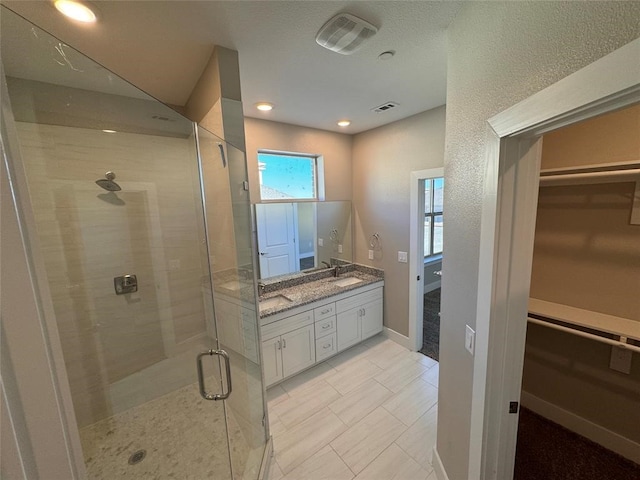 bathroom featuring a shower with door and vanity