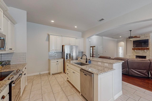 kitchen featuring a kitchen island with sink, sink, white cabinets, stainless steel appliances, and ceiling fan