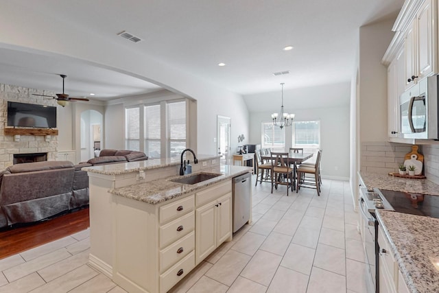 kitchen with hanging light fixtures, sink, tasteful backsplash, a center island with sink, and stainless steel appliances