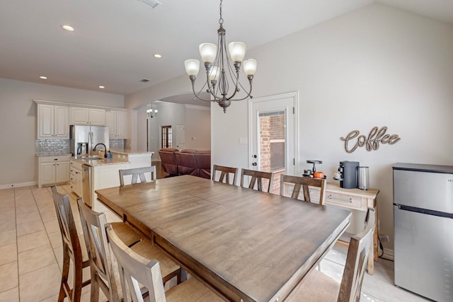 tiled dining room with a chandelier and vaulted ceiling