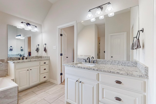 bathroom with lofted ceiling, vanity, a washtub, and tile patterned flooring