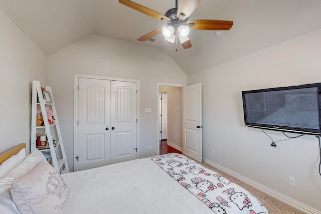 carpeted bedroom with ceiling fan, a closet, and vaulted ceiling