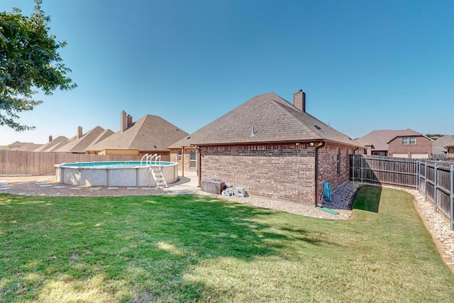 rear view of house with a fenced in pool and a yard