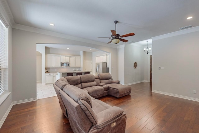 living room featuring ornamental molding, ceiling fan with notable chandelier, and hardwood / wood-style floors