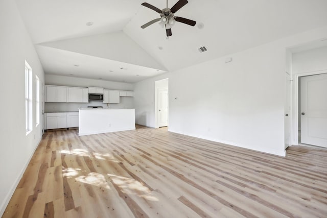 unfurnished living room featuring high vaulted ceiling, light wood-style flooring, visible vents, baseboards, and a ceiling fan