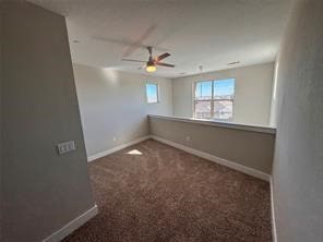 spare room featuring dark colored carpet and ceiling fan