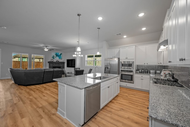 kitchen with an island with sink, white cabinetry, appliances with stainless steel finishes, and light hardwood / wood-style flooring