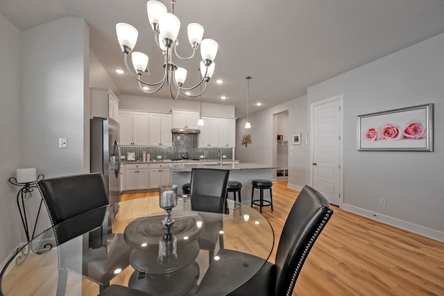 dining space with light hardwood / wood-style flooring, a chandelier, and sink