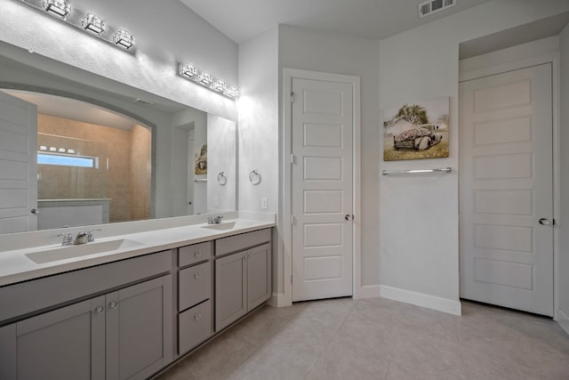 bathroom with tiled shower, vanity, and tile patterned floors