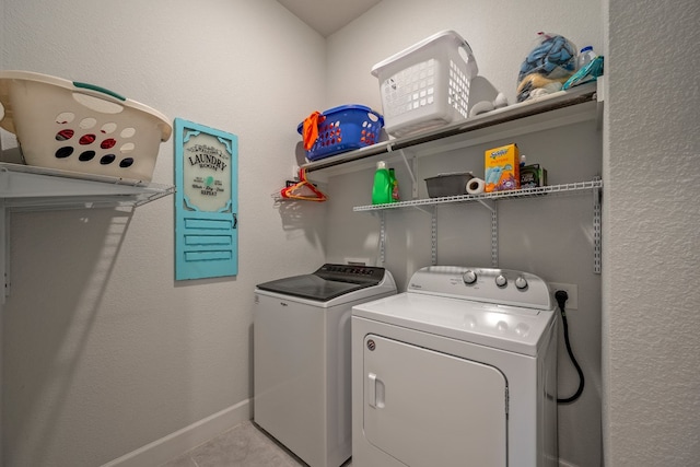 clothes washing area featuring light tile patterned floors and washer and dryer