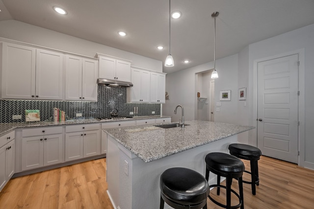 kitchen featuring a kitchen island with sink, sink, and white cabinets