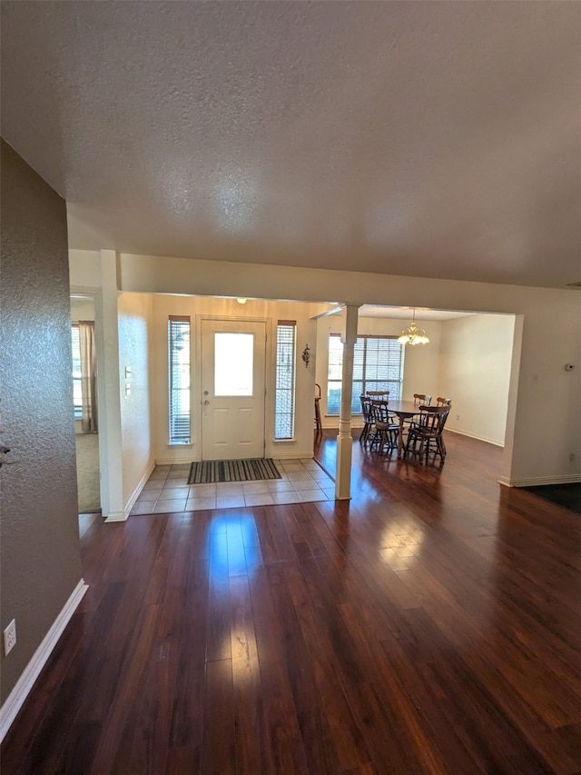 entryway with a notable chandelier, a textured ceiling, and dark wood-type flooring