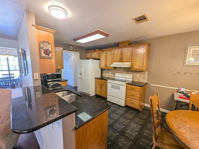 kitchen featuring kitchen peninsula, backsplash, dark stone countertops, sink, and white appliances