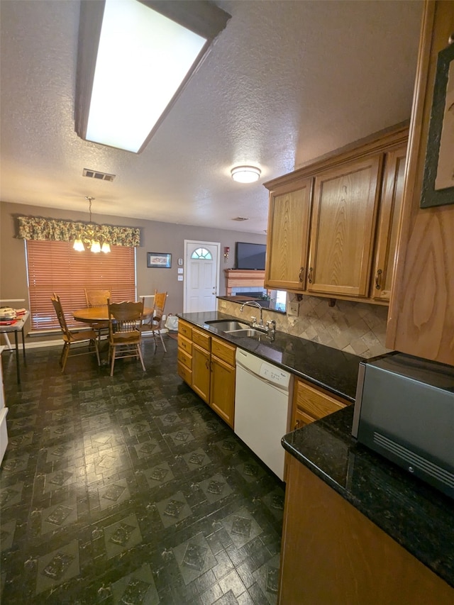 kitchen featuring sink, dishwasher, a textured ceiling, decorative light fixtures, and an inviting chandelier