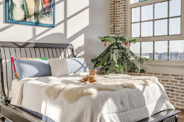 bedroom featuring brick wall, hardwood / wood-style flooring, and multiple windows