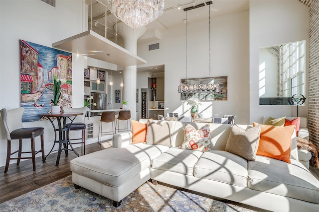 living room featuring a towering ceiling, dark wood-type flooring, and a chandelier