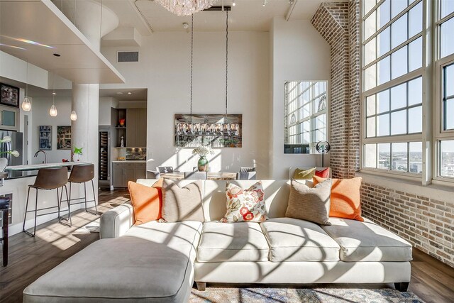 2600 W 7th St Unit 2746, Fort Worth, TX 76107 - living room featuring a towering ceiling, wood finished floors, brick wall, and a chandelier