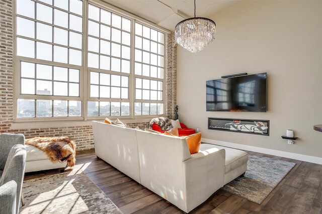 2600 W 7th St Unit 2746, Fort Worth, TX 76107 - living room with wood finished floors, a chandelier, brick wall, baseboards, and a high ceiling