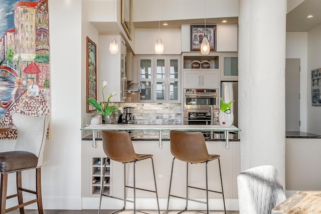 bar featuring dark stone countertops, pendant lighting, stainless steel appliances, and tasteful backsplash