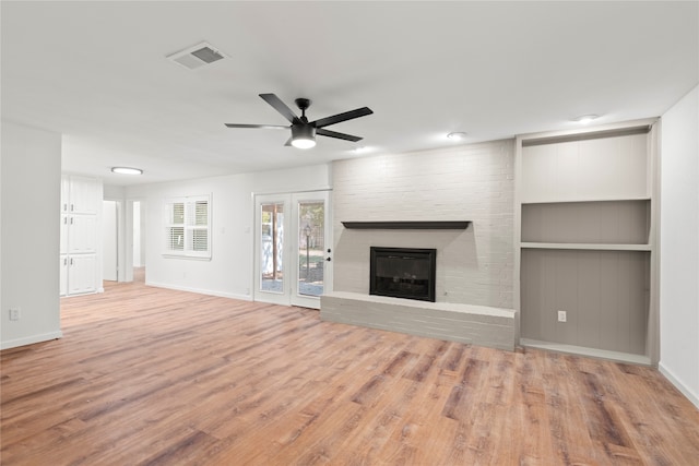 unfurnished living room with a brick fireplace, light hardwood / wood-style flooring, and ceiling fan