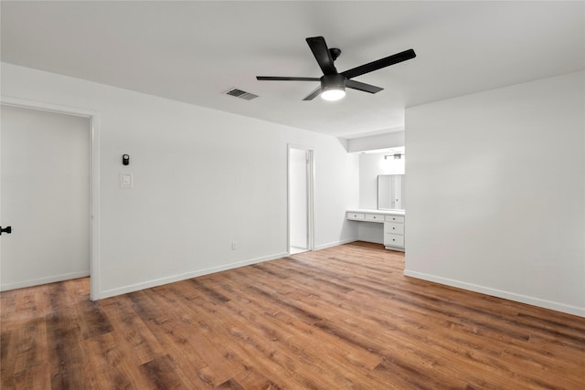 interior space featuring a ceiling fan, visible vents, baseboards, and wood finished floors