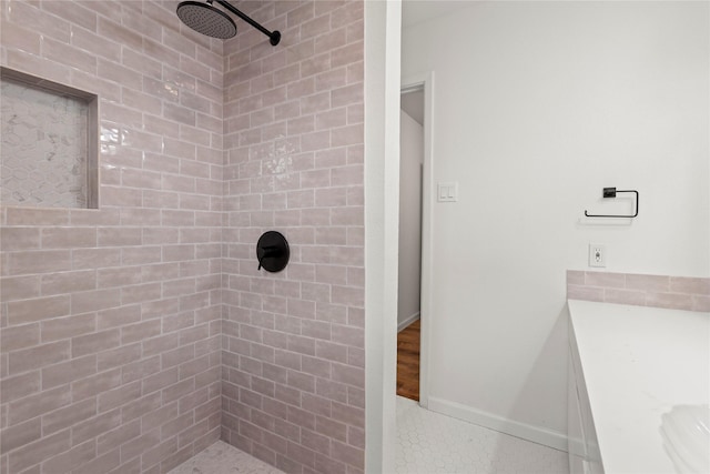 bathroom featuring a tile shower, baseboards, and tile patterned floors