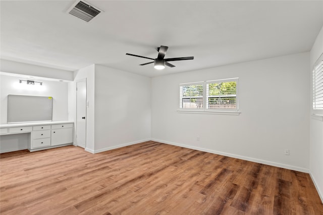 unfurnished bedroom with ceiling fan, built in desk, and wood-type flooring