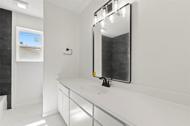 bathroom featuring a tile shower, vanity, and tile patterned flooring