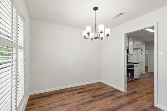 unfurnished dining area with dark hardwood / wood-style floors and a chandelier