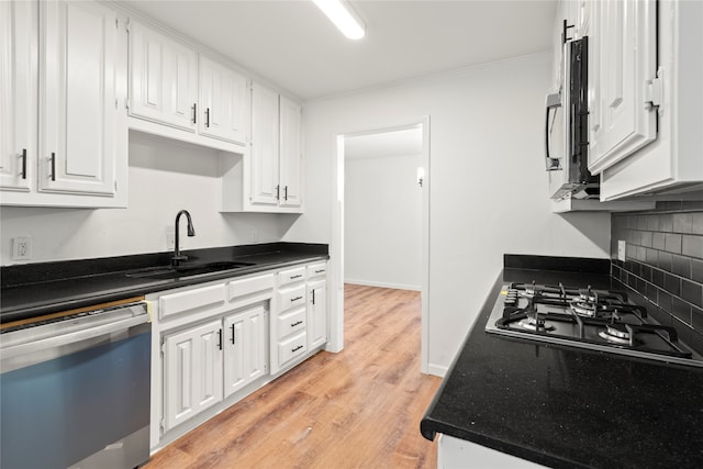 kitchen featuring appliances with stainless steel finishes, light hardwood / wood-style floors, tasteful backsplash, white cabinets, and sink