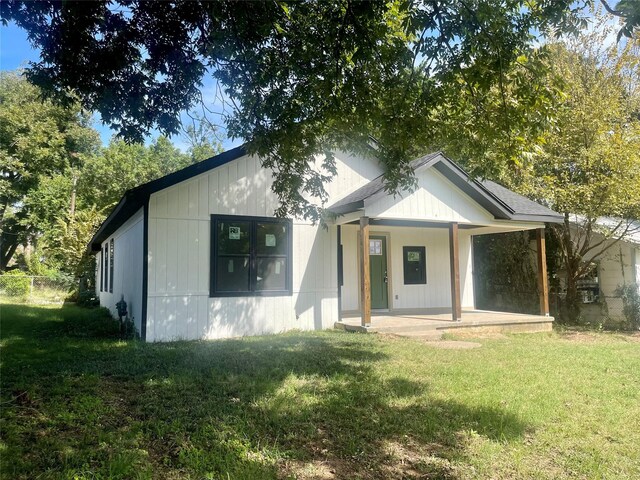 back of property featuring a lawn and covered porch