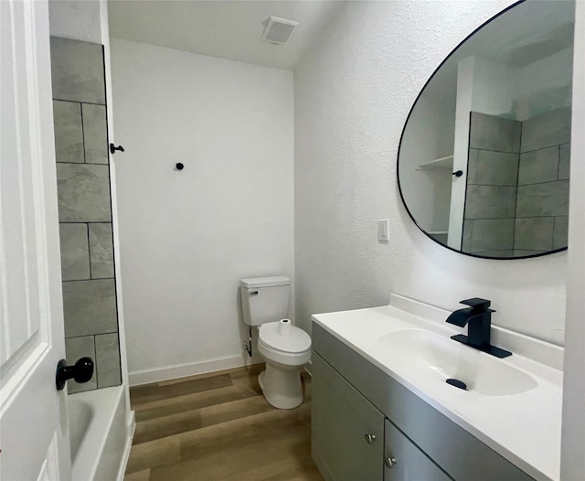 full bathroom featuring tiled shower / bath, vanity, hardwood / wood-style floors, and toilet