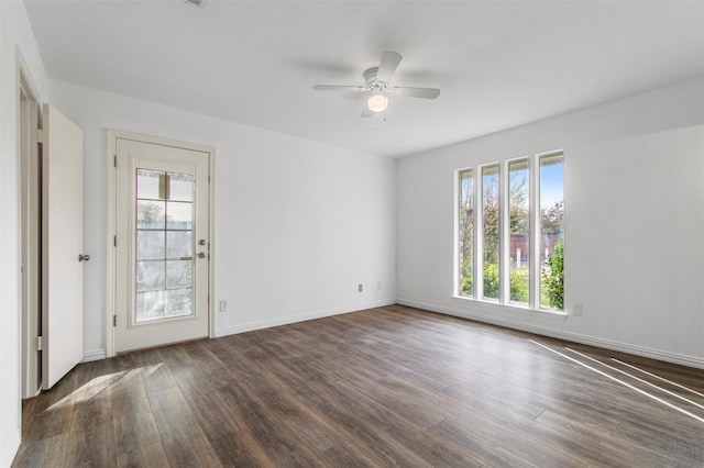 spare room featuring ceiling fan, a healthy amount of sunlight, and dark wood-type flooring