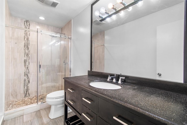 bathroom with tile patterned floors, vanity, toilet, and walk in shower