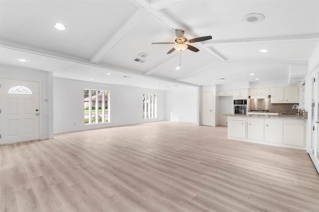 unfurnished living room with vaulted ceiling with beams, ceiling fan, light hardwood / wood-style flooring, and sink