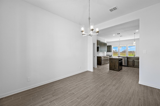 kitchen with sink, dark brown cabinets, a center island, hardwood / wood-style flooring, and a chandelier