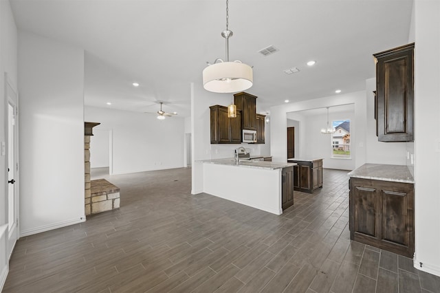 kitchen with appliances with stainless steel finishes, kitchen peninsula, decorative light fixtures, and dark hardwood / wood-style flooring