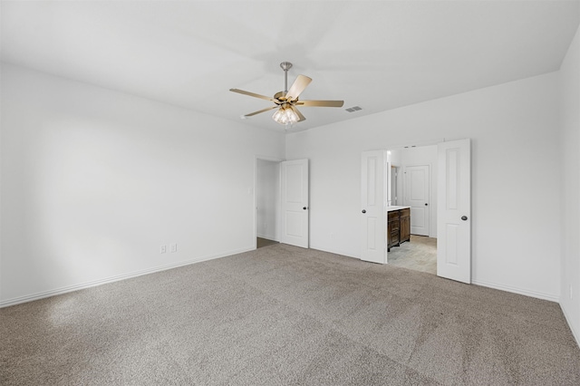 unfurnished bedroom with light carpet, ensuite bathroom, and ceiling fan