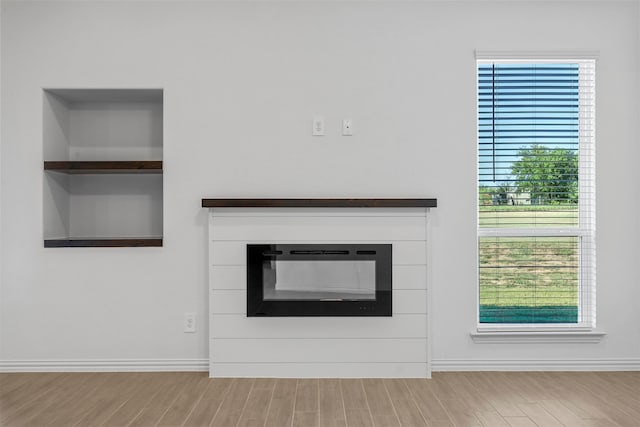 unfurnished living room featuring built in features and light hardwood / wood-style floors