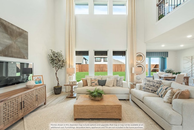 living room with light wood-type flooring and a towering ceiling