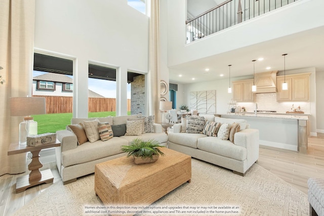 living room with a towering ceiling and light hardwood / wood-style flooring