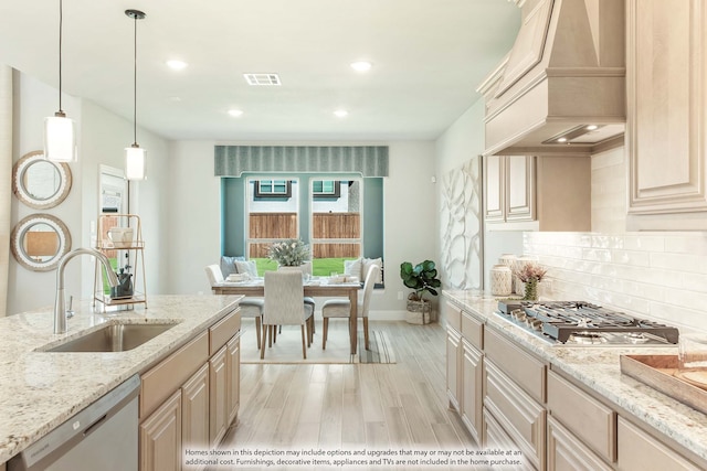 kitchen featuring premium range hood, hanging light fixtures, sink, appliances with stainless steel finishes, and light hardwood / wood-style floors