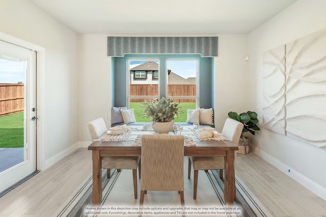 dining space featuring light wood-type flooring and a healthy amount of sunlight